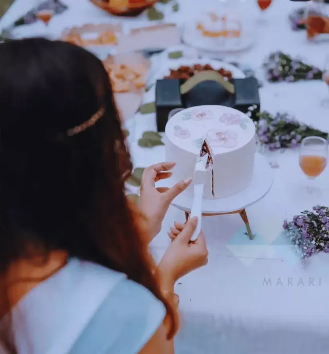 Bride-to-be cutting a white cake at a garden party