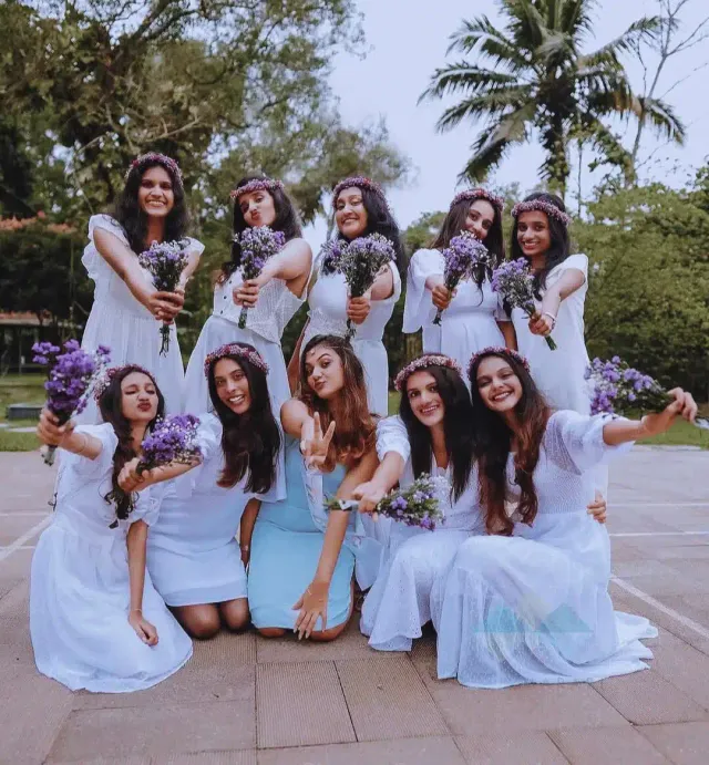 Bridesmaids in white posing with lavender bouquets