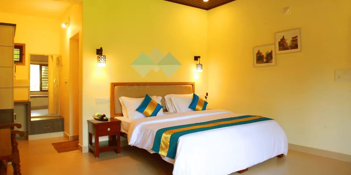 Deluxe AC room at Casa Marari with a king bed, striped throw and bedside lamps