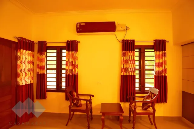 Sitting area with wooden chairs and table in a Deluxe AC room
