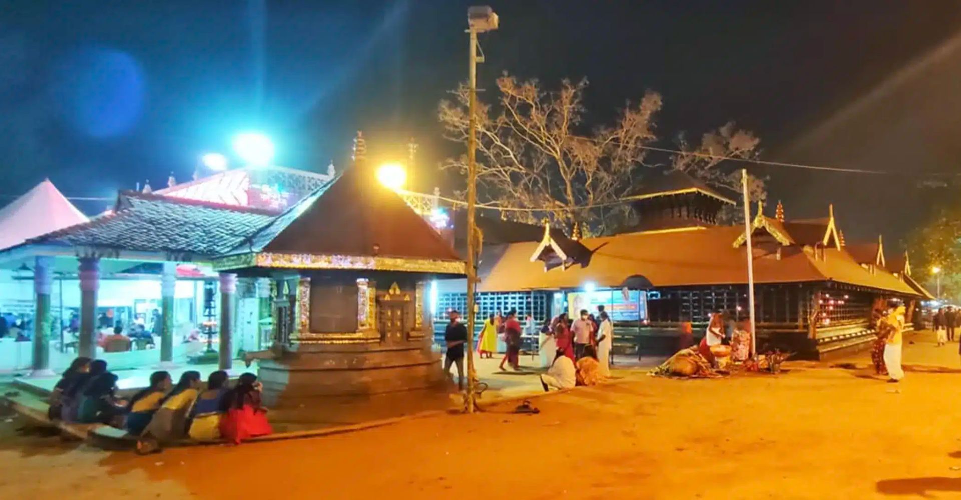 Kanichukulangara Devi Temple lit up at night with devotees in the courtyard