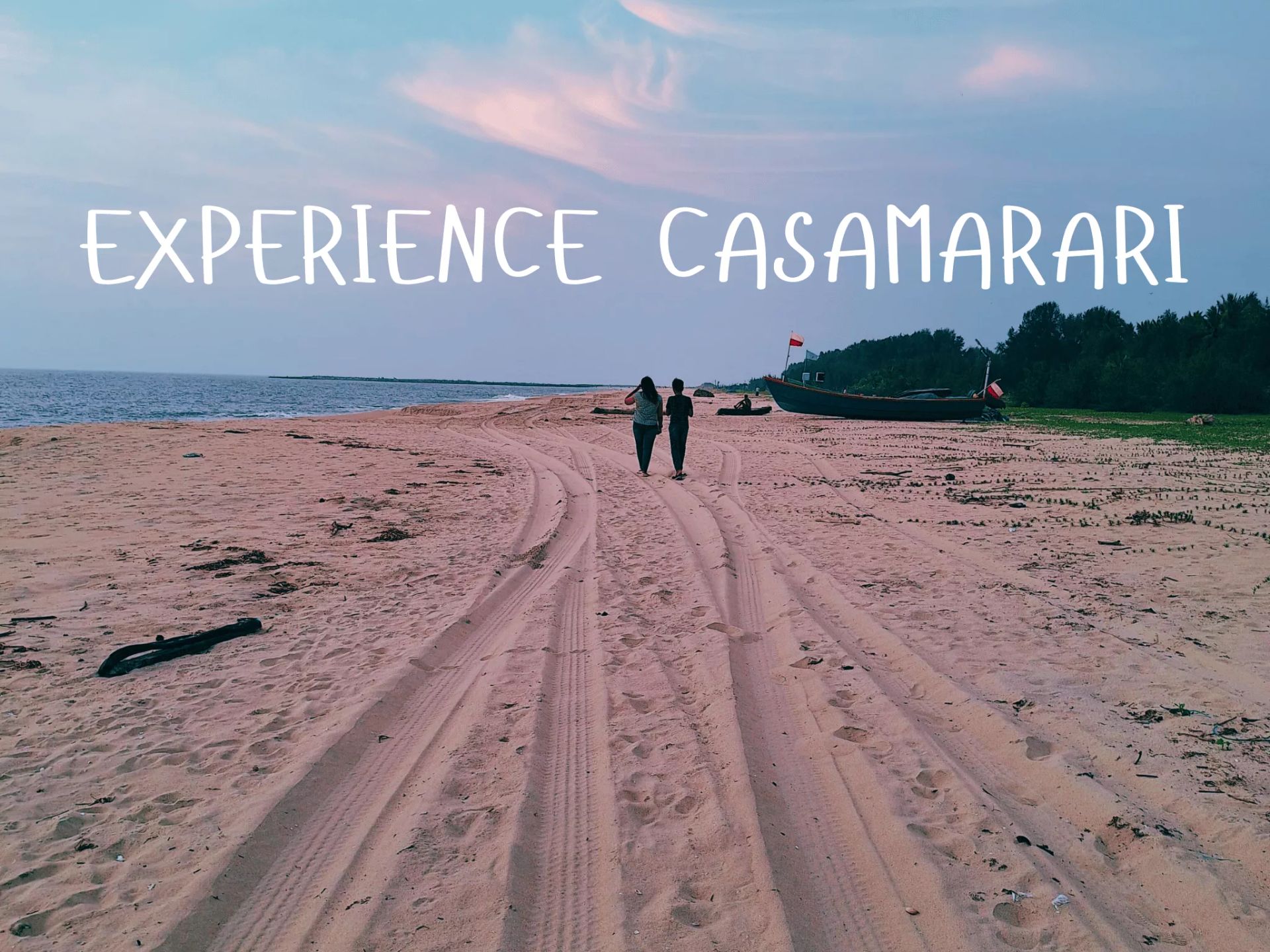 A couple walking along Marari Beach at dusk