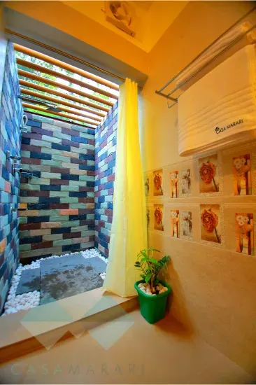 Open-to-sky shower with mosaic tile walls in a Deluxe room bathroom